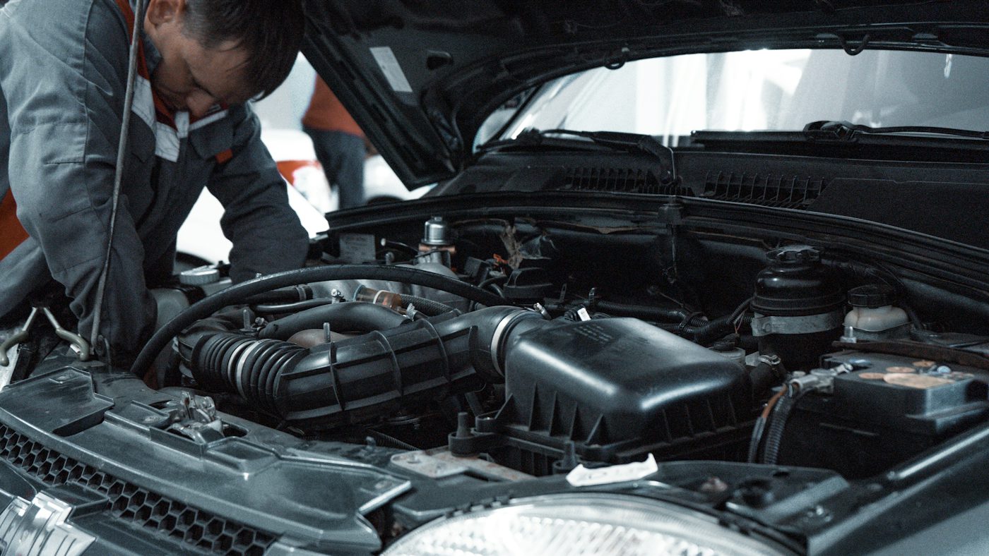 Technician working under the hood in a service bay